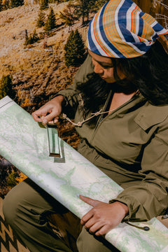 Woman wearing the Sage Tackle suite and Magnifier Necklace, wearing a bandana and looking at a map